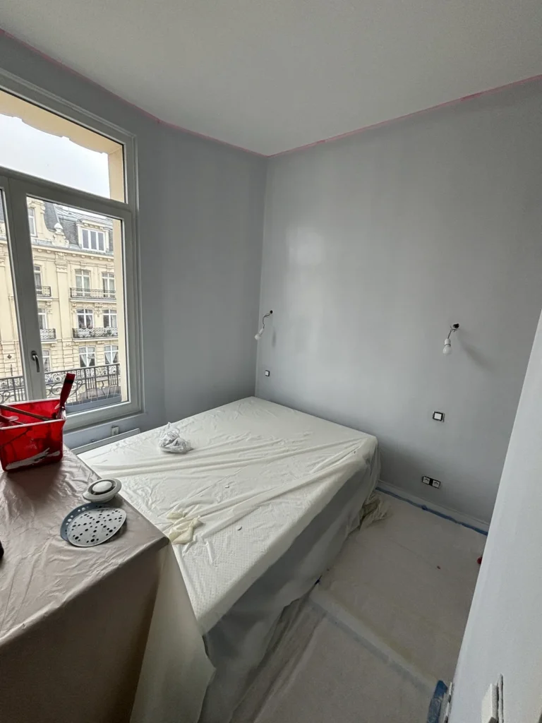 Chambre repeinte en gris clair avec porte-fenêtre donnant sur un balcon, appartement lillois