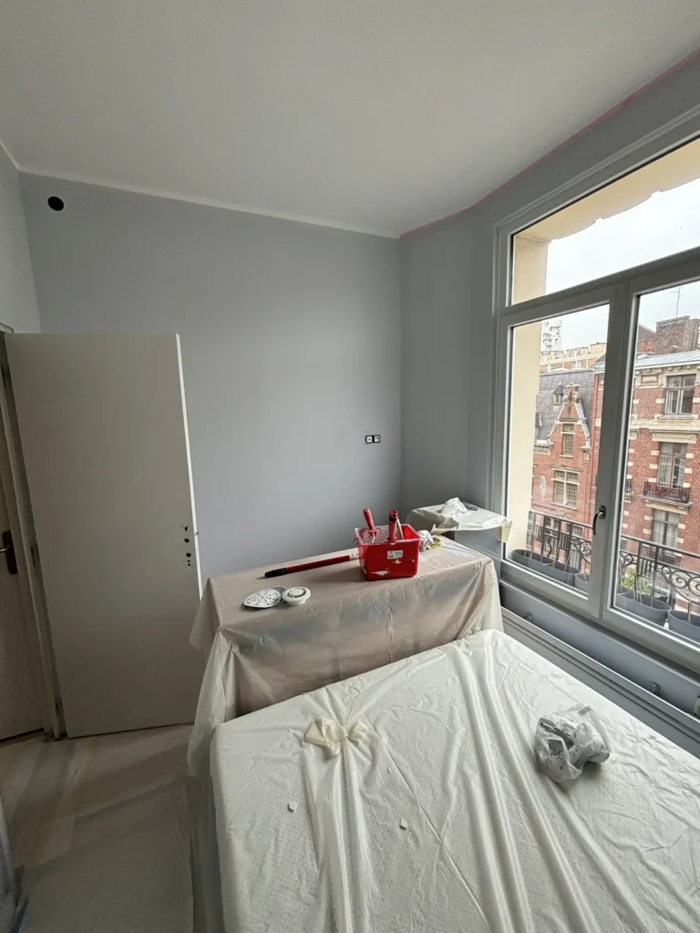 Chambre lilloise repeinte en gris avec bow-window donnant sur les façades en brique