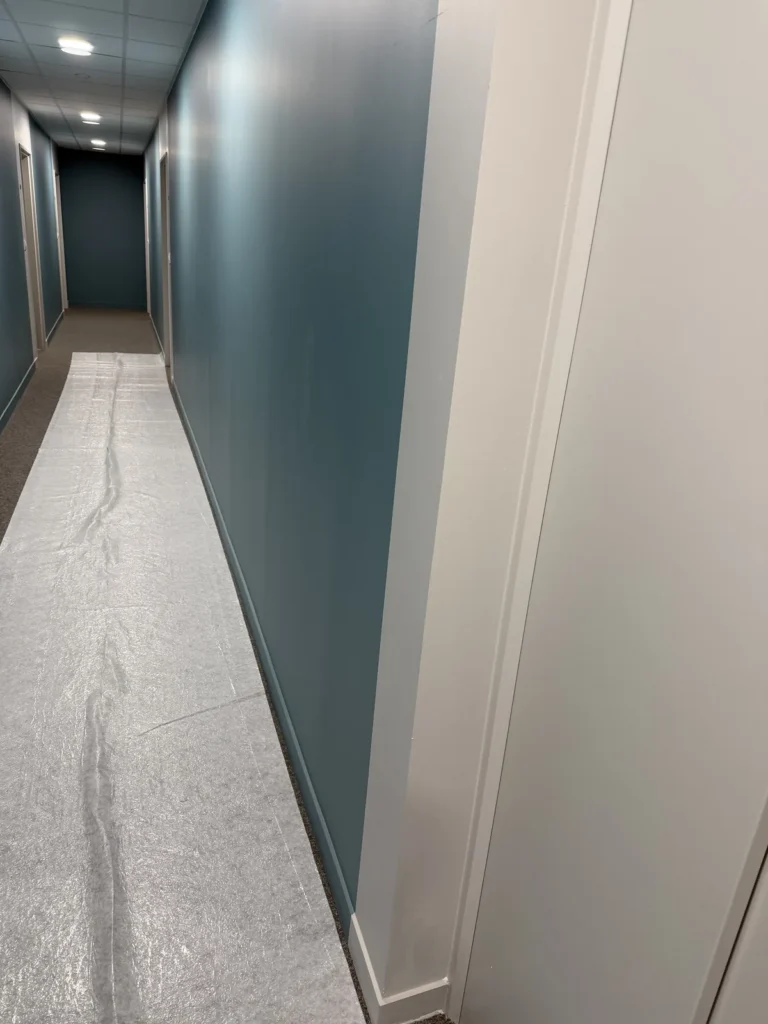 Couloir aux murs peints en bleu canard, sol protégé pendant les travaux de peinture à Arras
