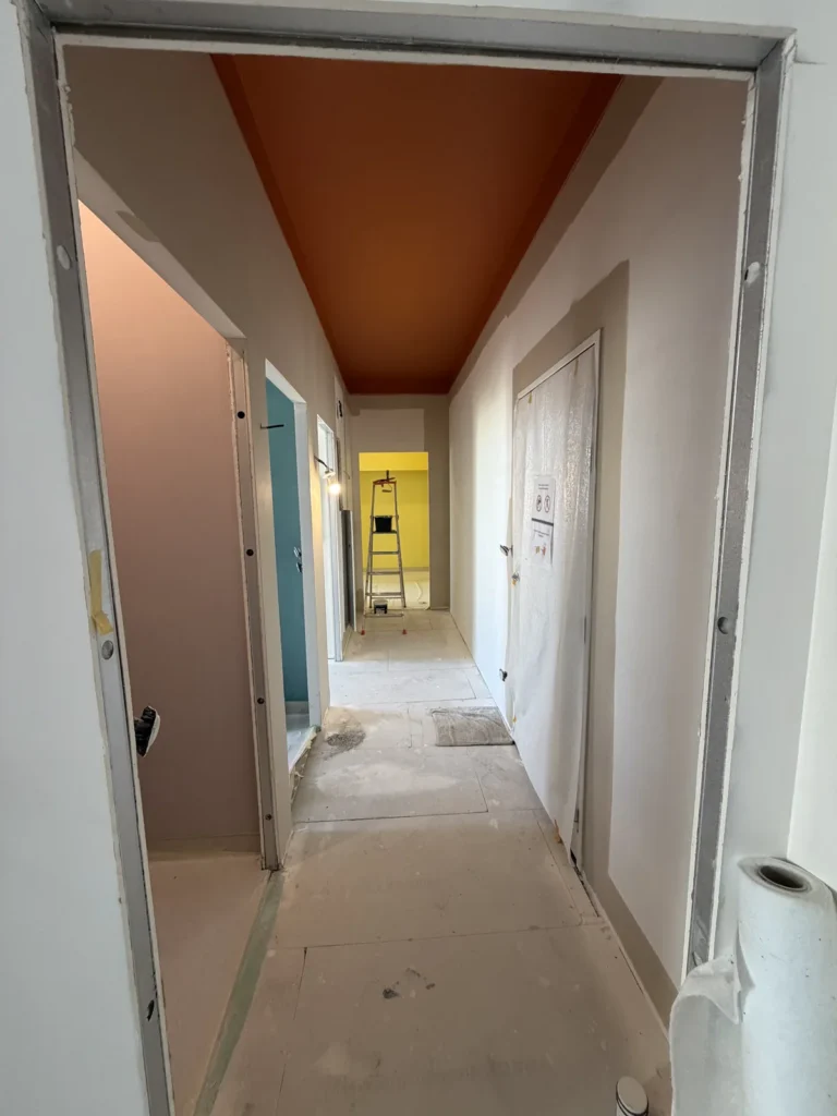 Couloir d’un appartement neuf à Arras avec plafond peint en terracotta, murs en cours de peinture par Achille Martin Décoration