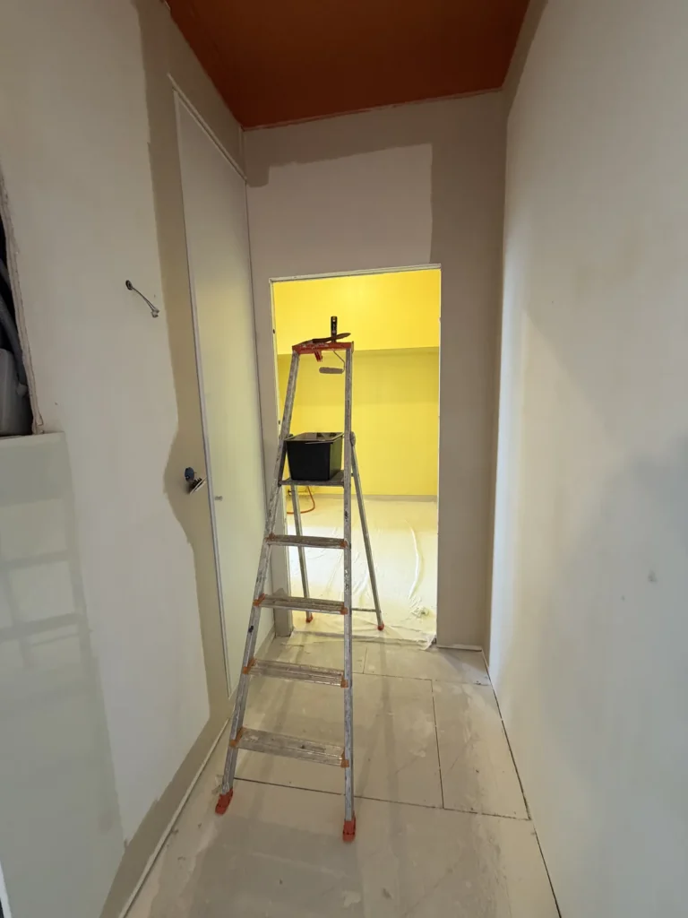 Dégagement de l’appartement d’Arras sous plafond terracotta ouvrant sur une pièce peinte en jaune