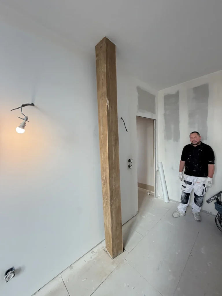 Peintre d’Achille Martin Décoration devant des plaques de plâtre neuves ratissées et une poutre en bois ancienne