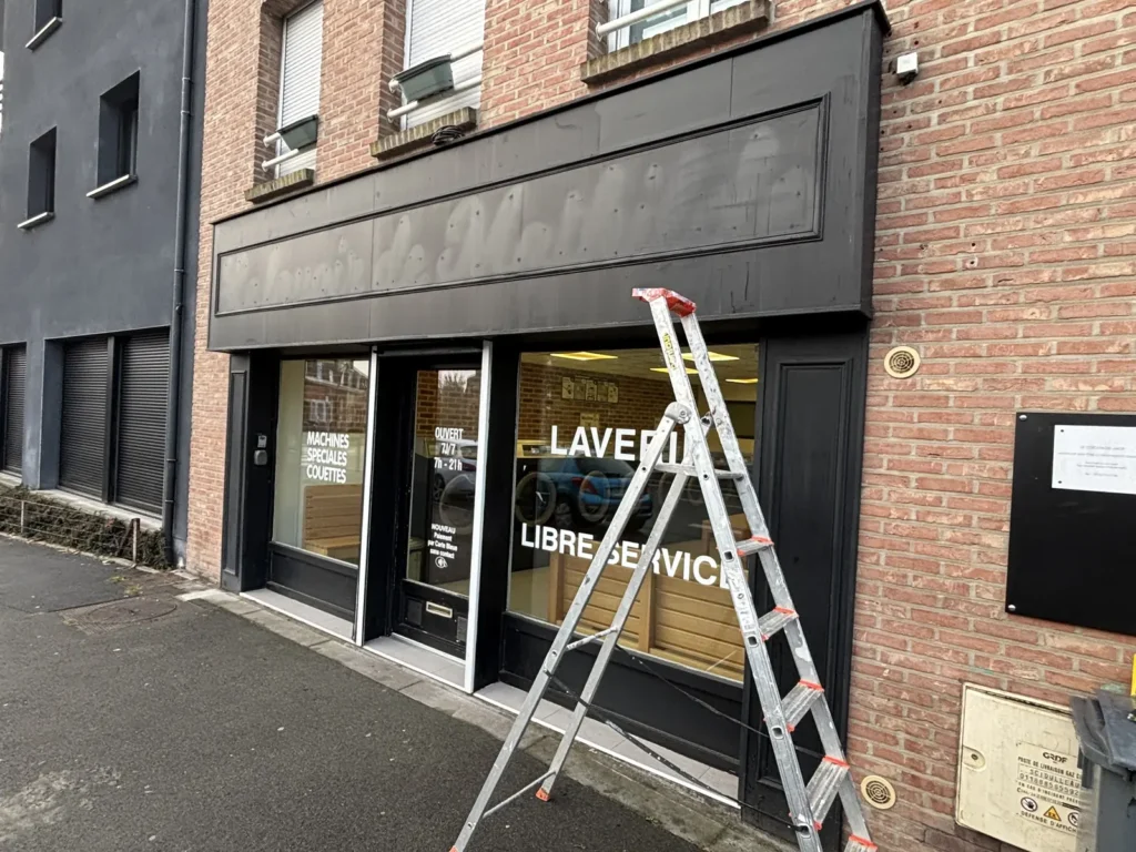 Devanture de la laverie de Wambrechies avant travaux, lettrage déposé et peinture des encadrements écaillée