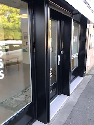 Porte d’entrée et encadrements de vitrines de la laverie repeints en noir satiné, plaques aluminium thermolaquées